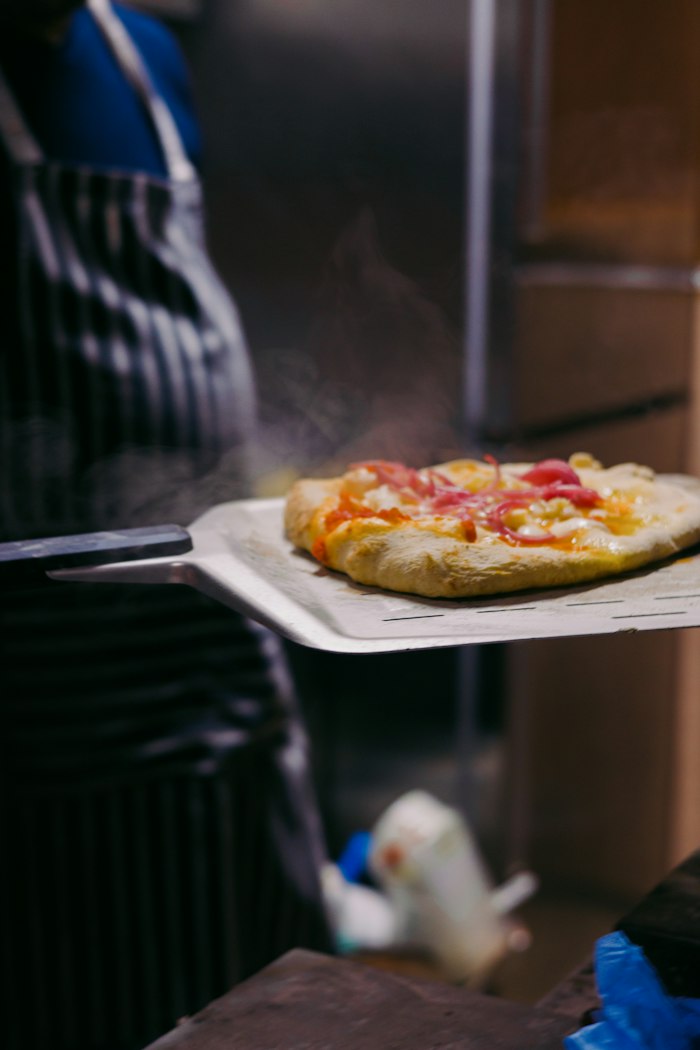Pizza maison garnie prête à enfourner sur son plat de service