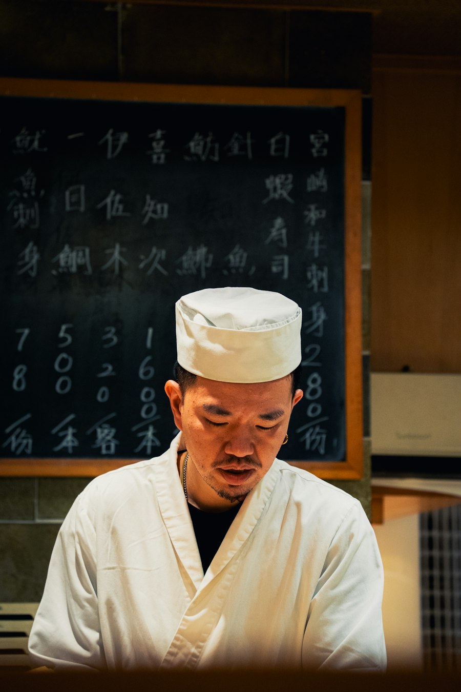 Chef en toque qui démontre une technique de cuisine devant son plan de travail